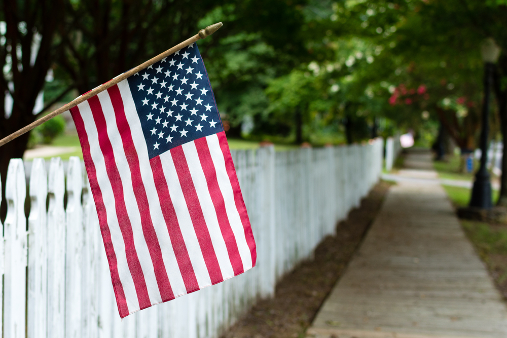 small American flag hangs from a picket fence
