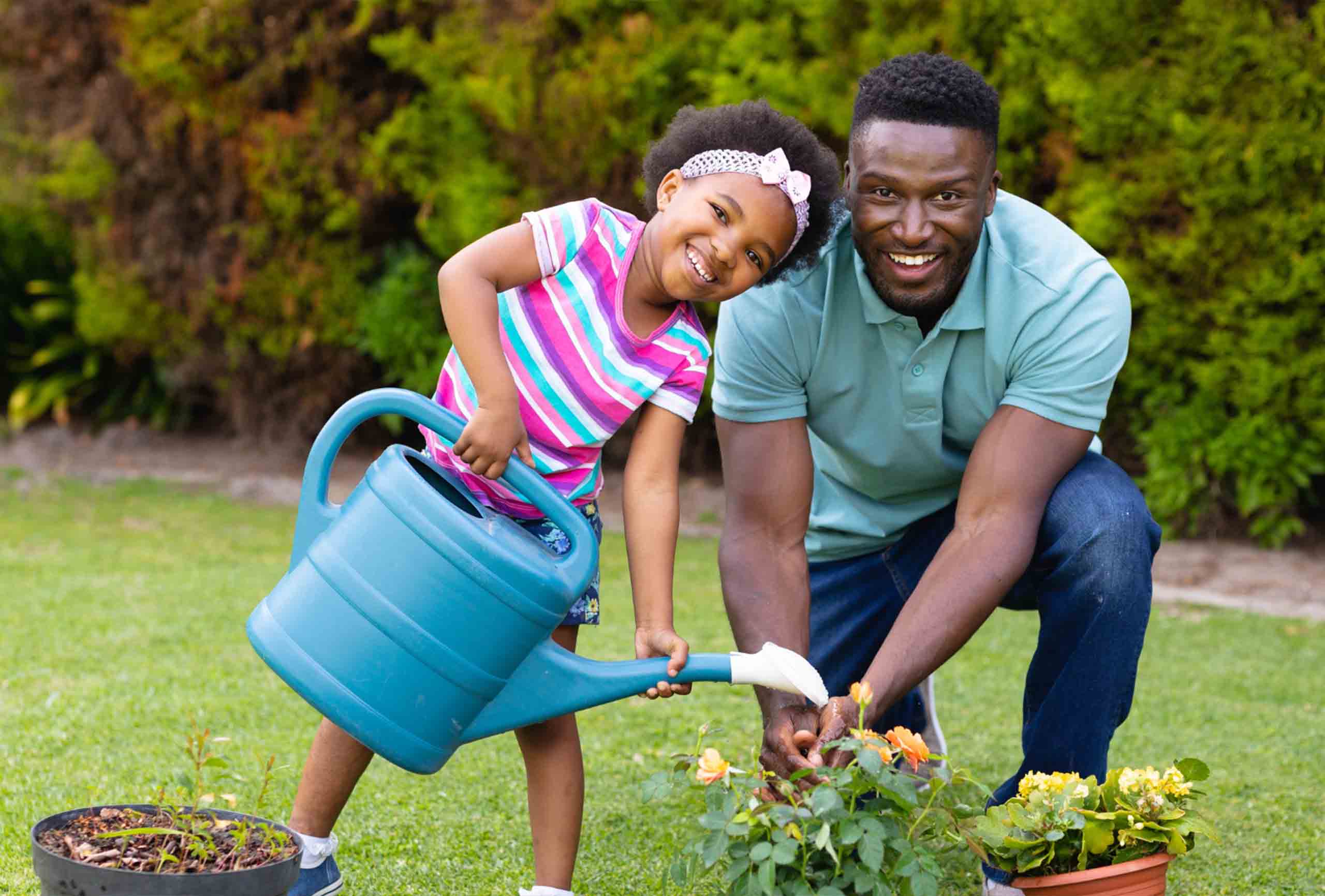 Father and daughter watering plant